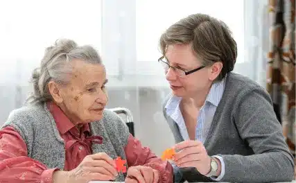 Caregiver assisting elderly woman with puzzle activity