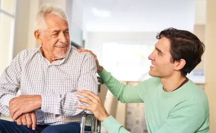 Young man helping senior man in wheelchair