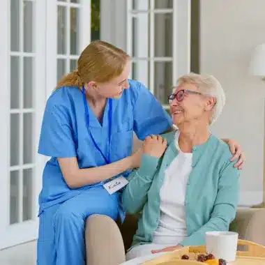 Nurse comforting senior woman at home